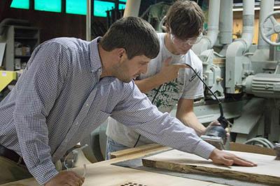 Chad Niman, UK forest products specialist, inspects Garrett Dunn’s work. Dunn, a forestry and natural resources student, was among several UK students who volunteered their time and skills to finishing the tabletops.