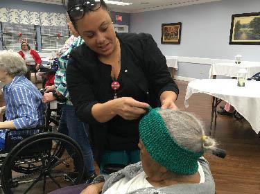 Pine Meadows employee Natasha Smith helps a resident try on a knitted headband.