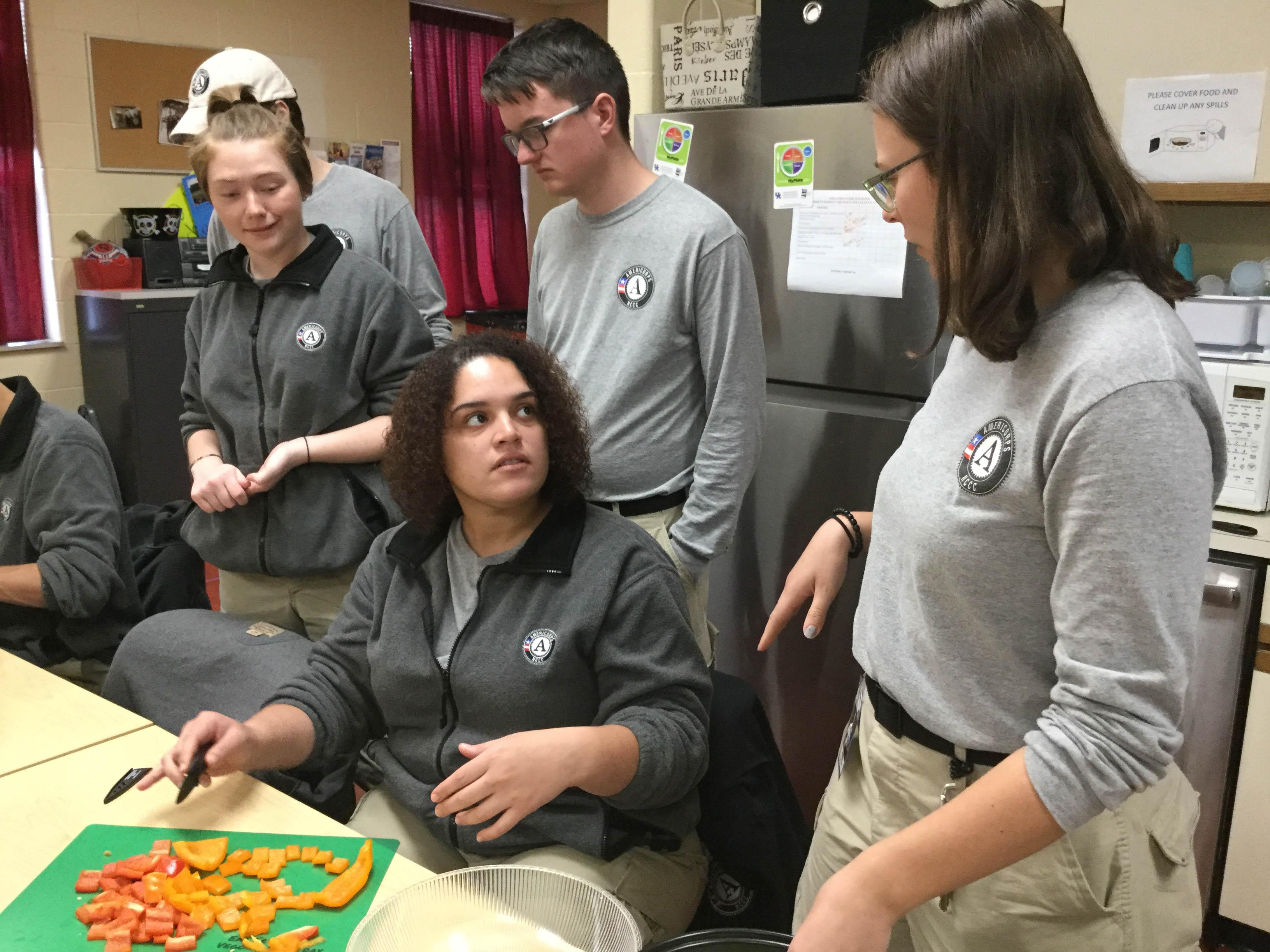 AmeriCorps team members gather around Claritza Sanchez, as the group begins prep for their lunch of skillet enchiladas. AmeriCorps team members gather around Claritza Sanchez, as the group begins prep for their lunch of skillet enchiladas.