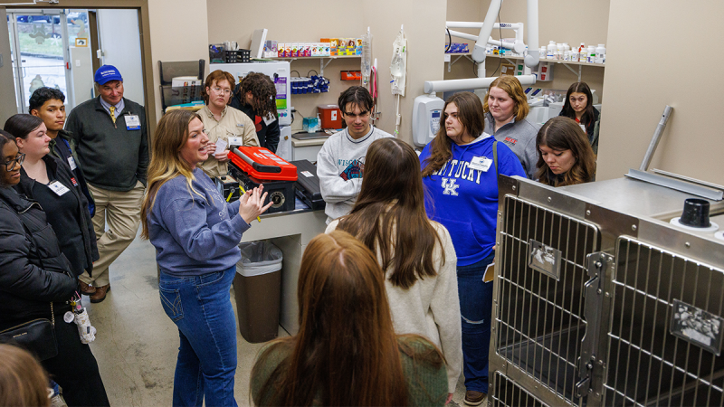 In a veterinary's office, a woman speaks to several college students. 