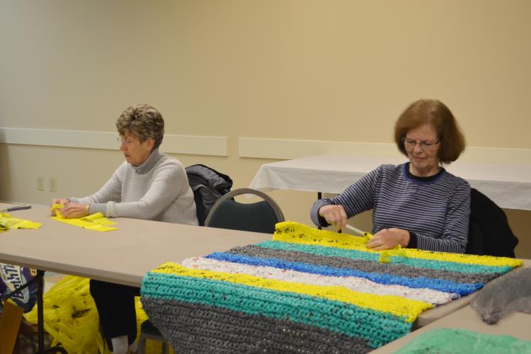 Boyd County Extension Homemaker Debbie Hoback, left, hooks together pieces of plastic bags to make "plarn" while fellow Extension Homemaker Lana Plymale crochets one of the mats. 