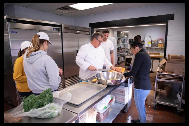 Chef Bob Perry instructs students how to slice a banana squash in DHN 342: Quantity Food Production. Mark Cornelison | UK Photo.