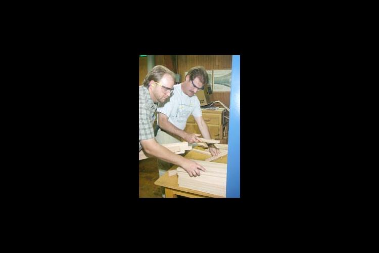 Bobby Ammerman (left), UK Wood Utilization Center Technical Advisor for the secondary wood industry, shows Glenn Brandl how to inspect pieces coming out of the moulder.