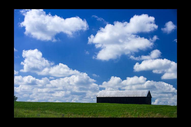 Clouds, blue sky, barn on a hill