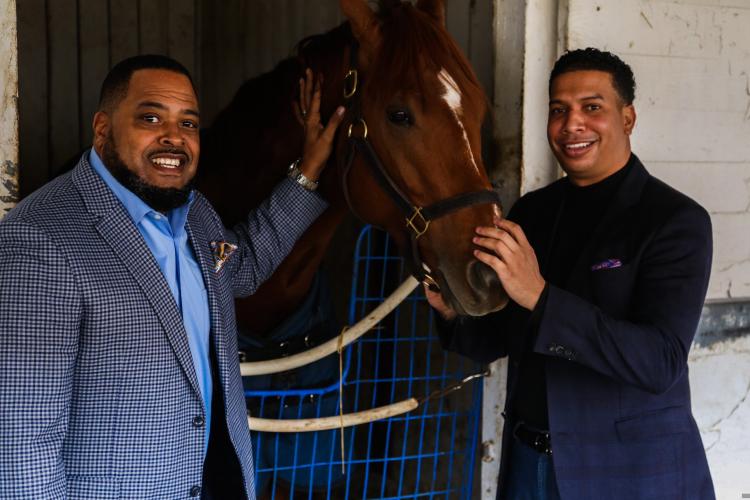 Ray Daniels and Greg Harbut pose by a Thoroughbred race horse.