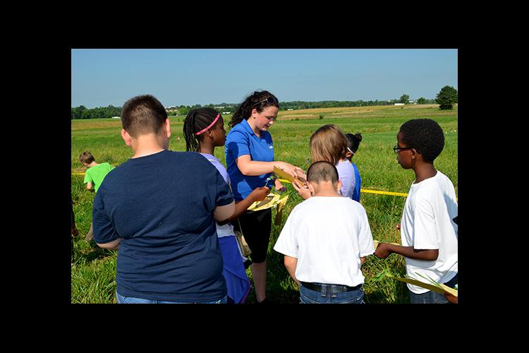 Sydney Beidleman, center, UK forage intern, helps Millcreek Elementary students identify weeds. 