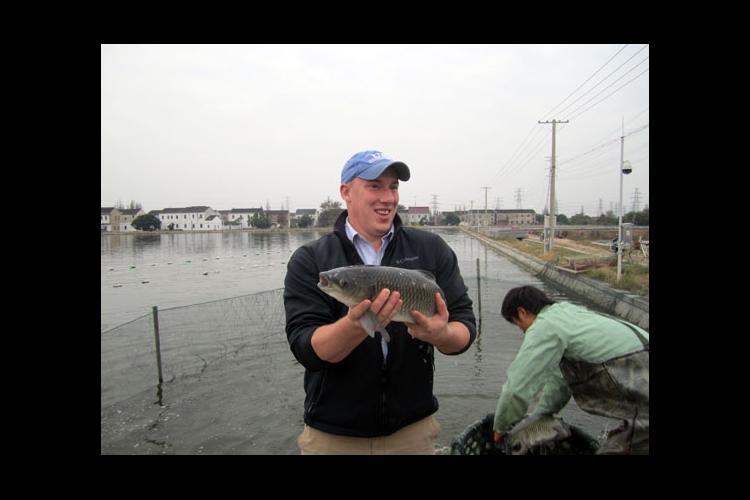 UK doctoral student John Orlowski holds a grass carp at a U.S. Soybean Export Council production demonstration in China.