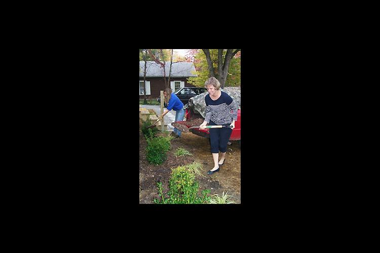 Elizabeth Rhoads, foreground, a member of the Hopkins County Horticulture Extension Council and Amy Fulcher, Hopkins County Extension agent for horticulture put mulch around newly planted landscaping at a home built by Habitat for Humanity in Madisonville