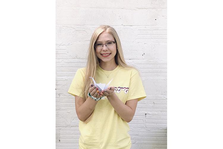 Lily Martin, Webster County 4-H'er and State 4-H Teen Council member, poses with one of the paper cranes she has made. Photo courtesy of Lily Martin.