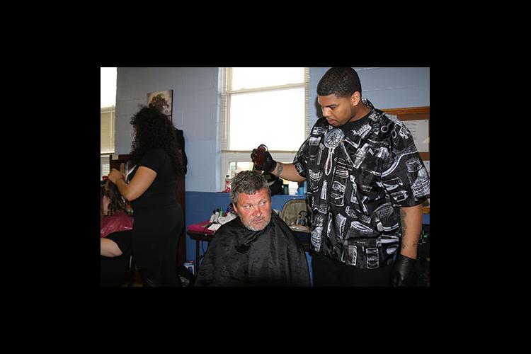 Brandon Merriweather cuts the hair of one of the men who came to the event at the New Life Day Center.