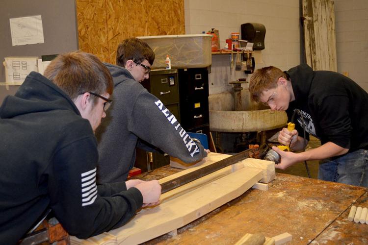 Wayne Johnson, a junior at Franklin-Simpson High School, drills holes in a headboard for dowel rods while Wyatt Shields, a junior, center, and Brandon Boyer,  a senior, left, secure the headboard. Photo by Katie Pratt, UK agricultural communications.