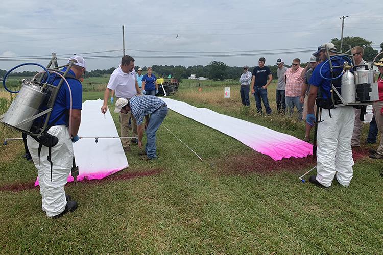 UK weed scientist Travis Legleiter, center, uses pink dye to demonstrate how nozzle size and boom height affect herbicide drift during the 2019 Spray Clinic. Photo by Lori Rogers, UK KATS coordinator.