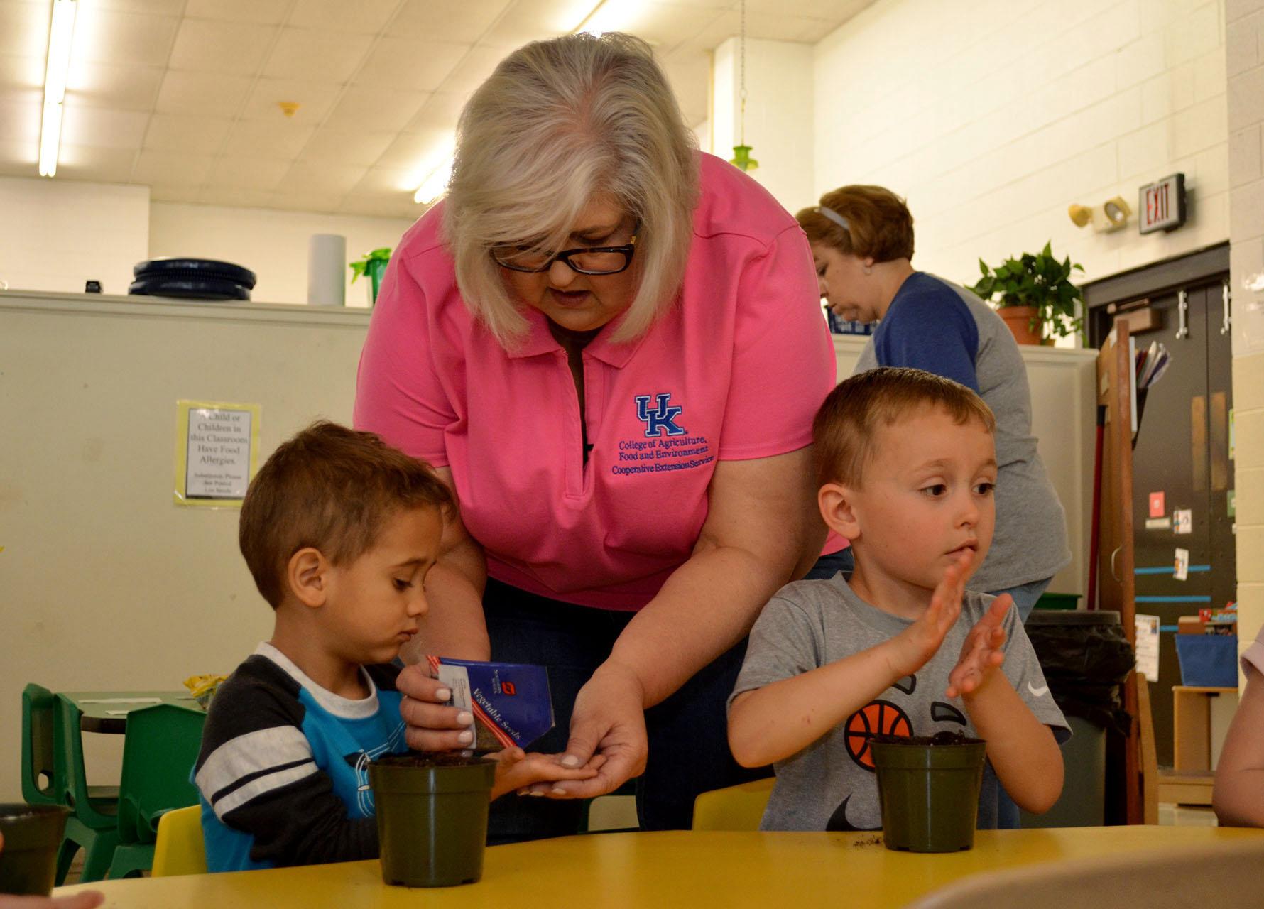 Boyd County horticulture extension agent Lori Bowling gives lettuce seeds to Jamar Higgs, left, as Talin Holbrook looks on. The boys are students at the Early Childhood Learning Center-North in Ashland. Photo by Katie Pratt, UK agricultural communications