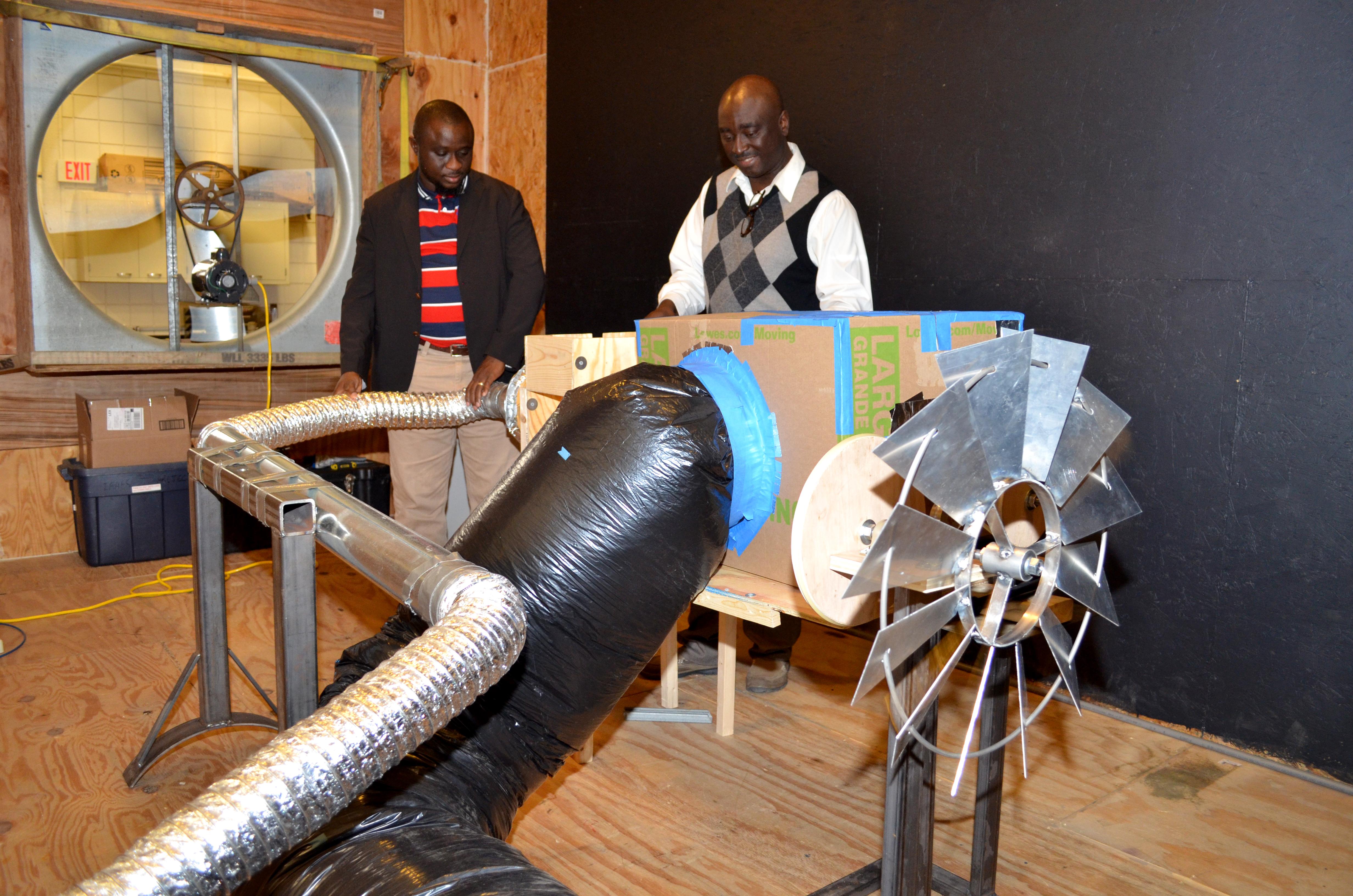 UK assistant professor Akinbode Adedeji and UK doctoral student Francis Agbali look over the wind turbine and grain drying system they developed.