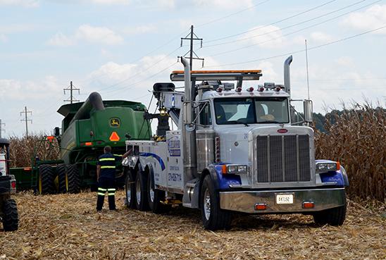 A wrecker removes a combine from a ditch. 