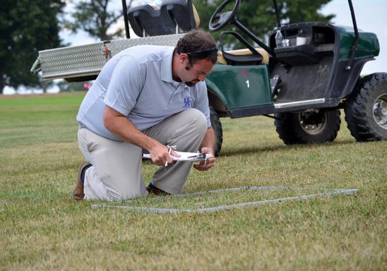 UK doctoral student Kenneth Cropper takes measurements in one of the lawn management systems at UK Spindletop Research Farm.