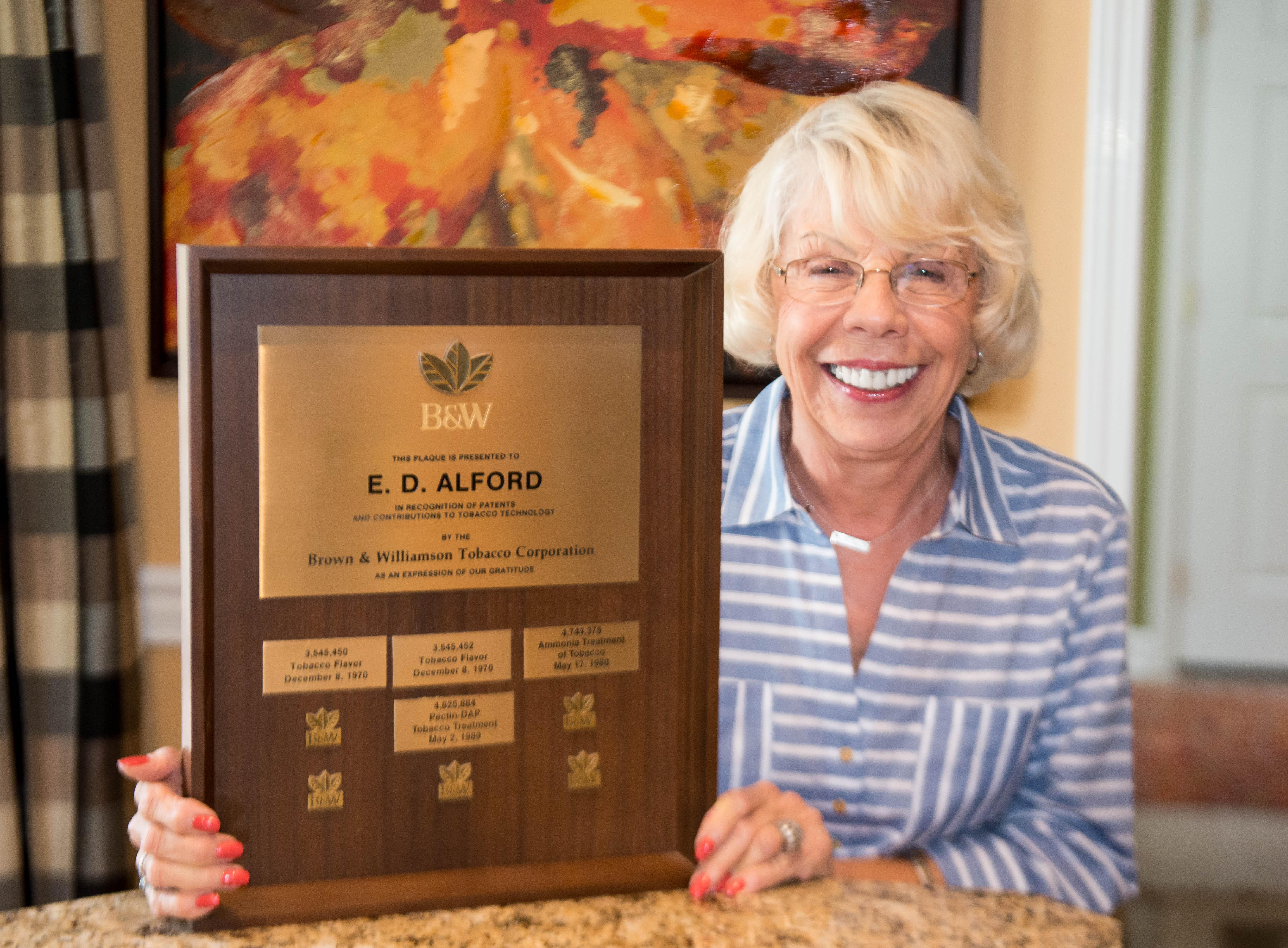 Donna Alford, holding a plaque of Demp Alford's patents 