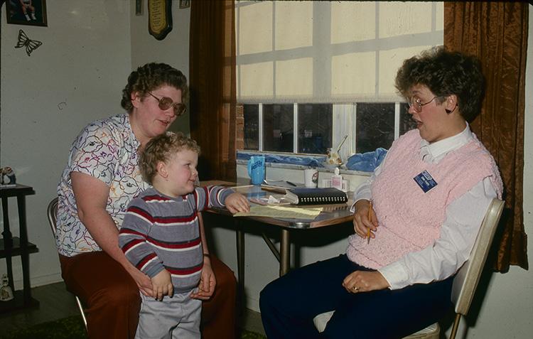 An archive photo of former Boyd County EFNEP assistant Donna Powers working with a family.