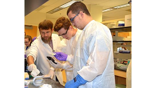Lou Hirsch, left, helps two Garrard County High School students learn how to extract DNA in a UK lab. 