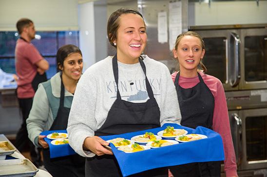 Taylor Runyon, center carries out recipes for taste test panelists at UK. UK students Monica Shah and Hannah Mayse follow. 