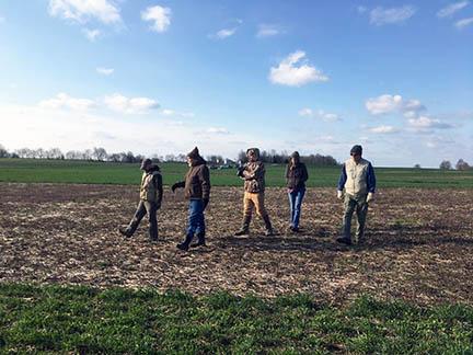 Researchers walk across one of Richard Preston's fields.