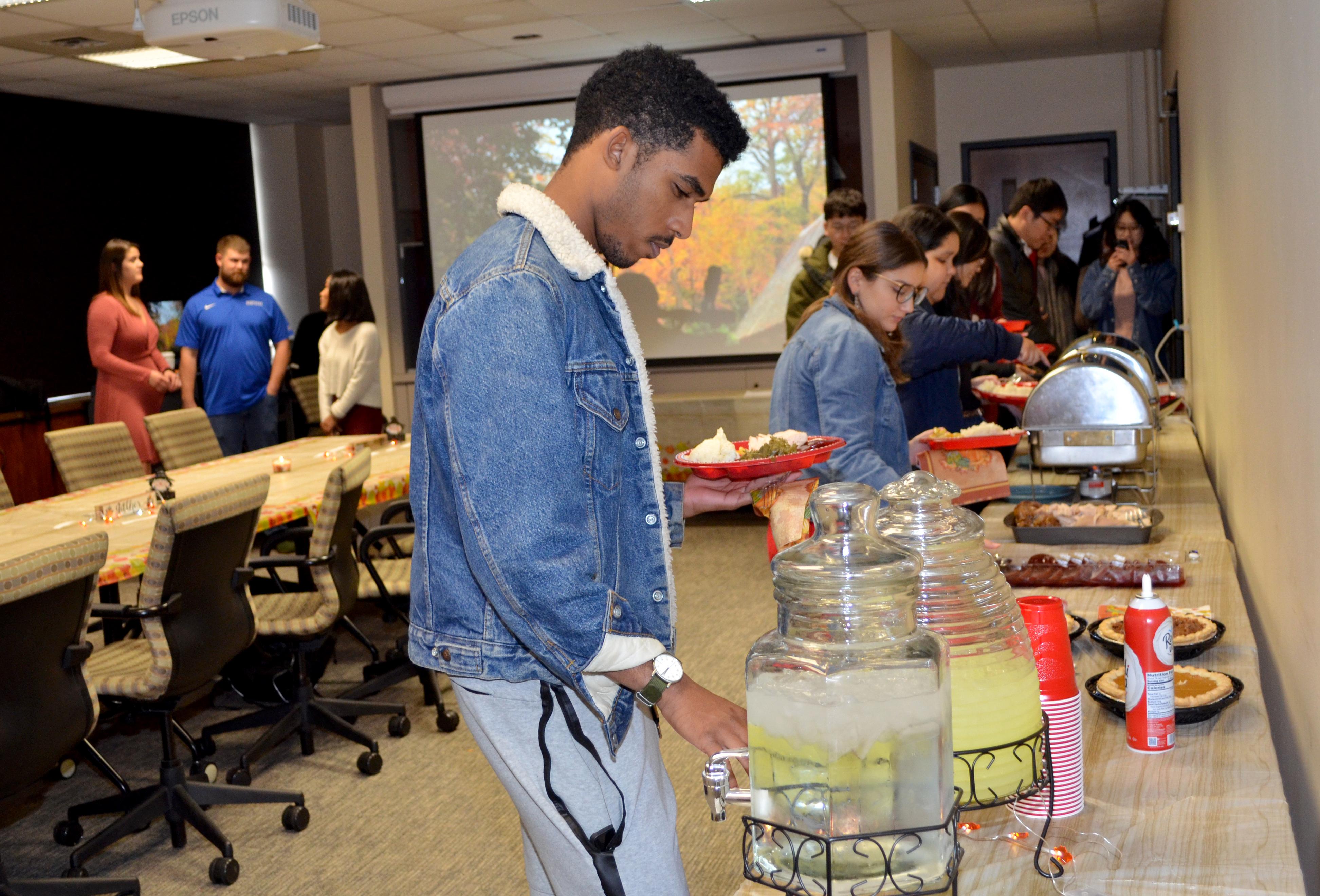 UK junior Ahmed Hamad pours some lemonade while making his way through the Thanksgiving buffet hosted by fellow UK students. Photo by Katie Pratt, UK agricultural communications.