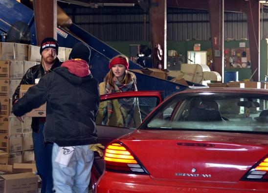 Cabrina Buckman, center, holds open a door for Alan Stubbs and another community volunteer as they fill cars with food. 