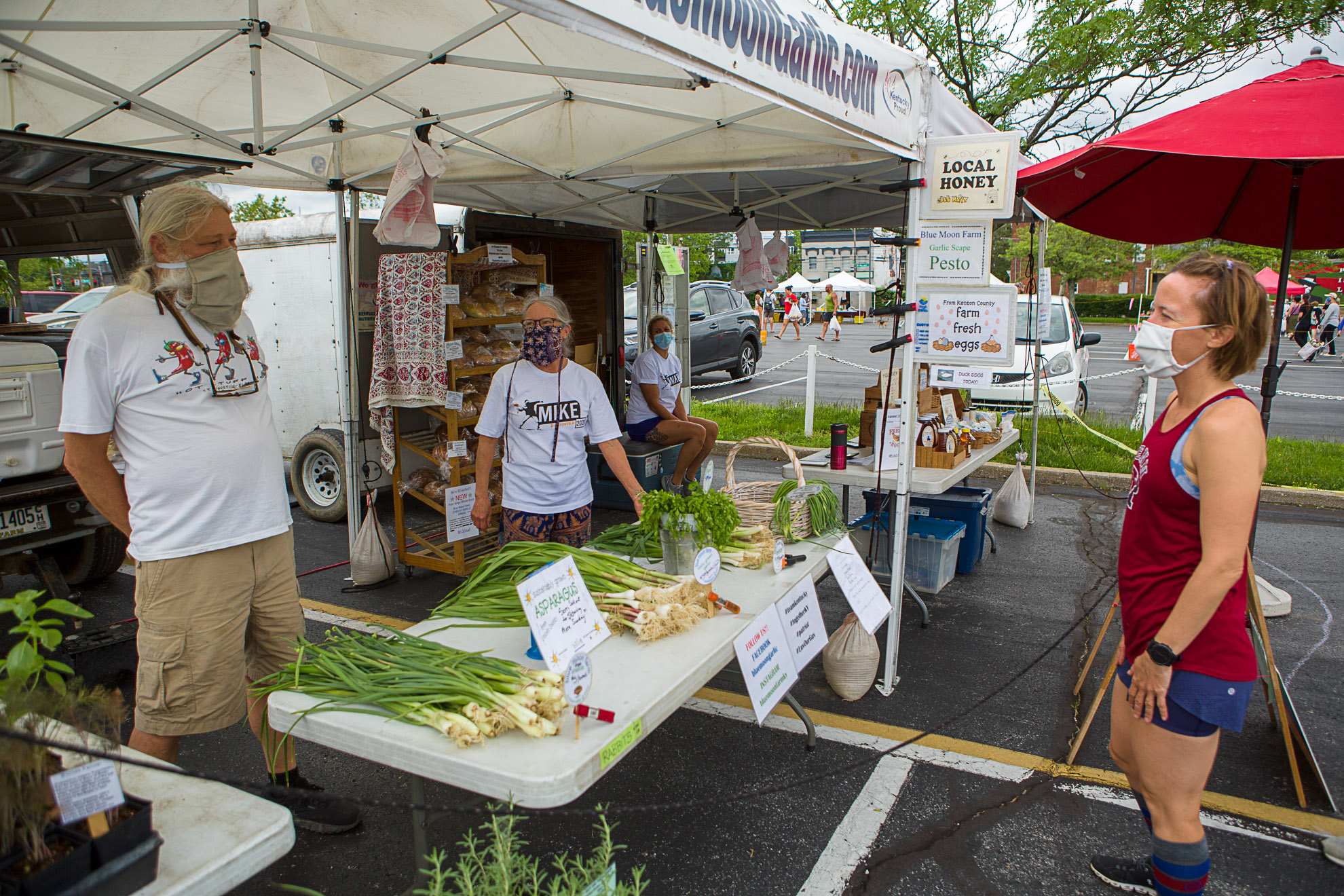 "No hugs for a while." Leo and Jean Keene, Blue Moon Garlic Farm, practice safe-distancing from long-time customers at the Lexington Farmers Market. Photo by Matt Barton