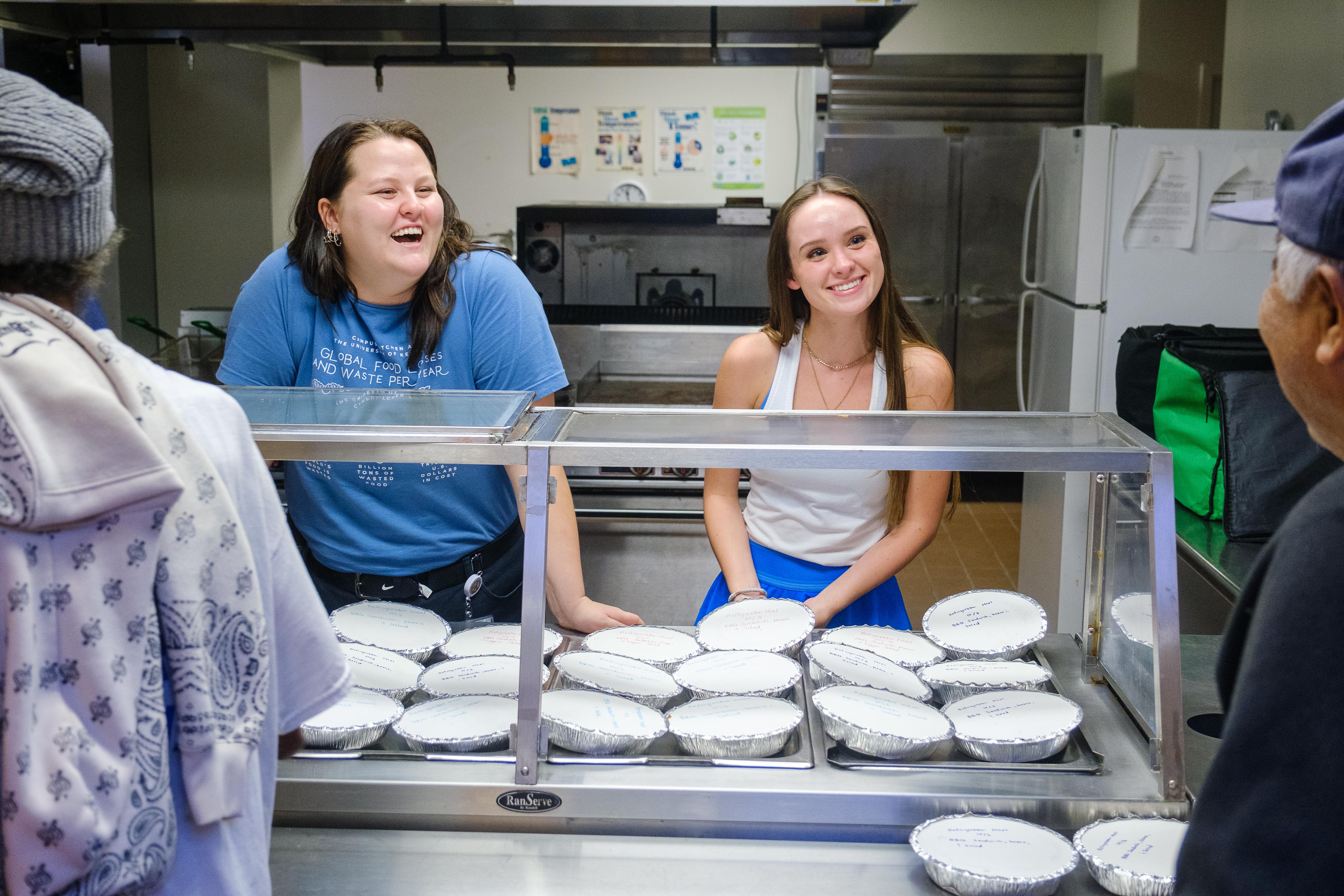 Sophia Bonilla and Katie Martin serving meals to residents.