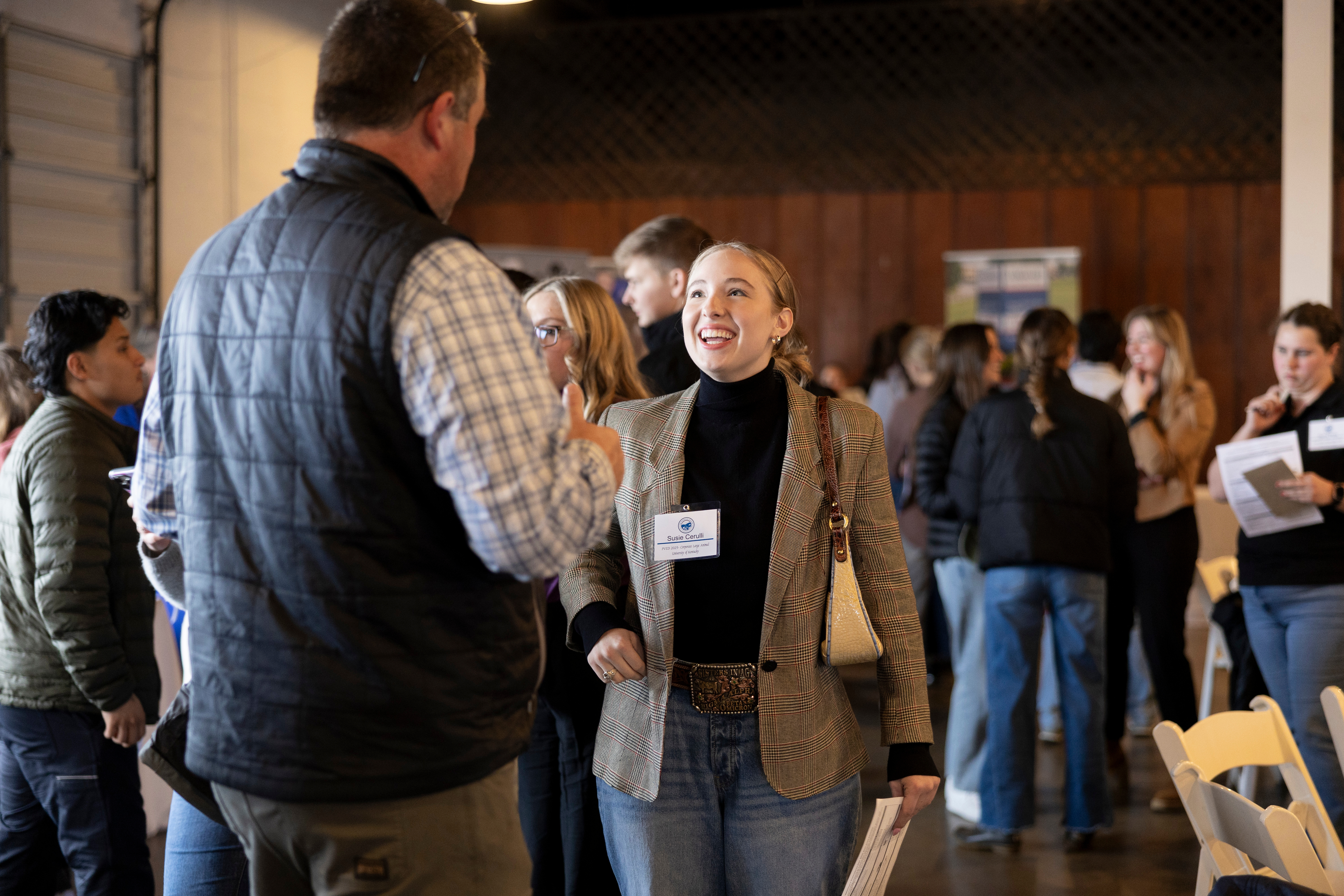 A young woman smiles as she talks to a tall man, whose back is to the camera. 