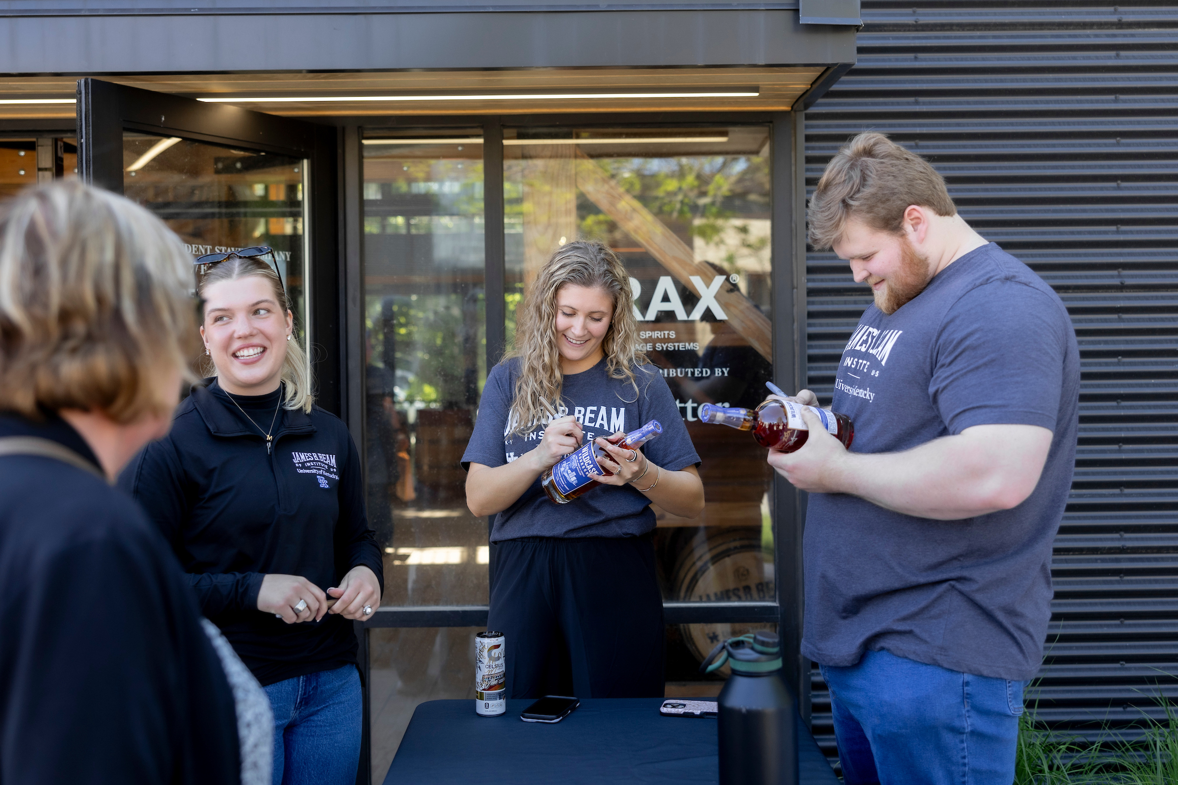 Three students outside of the Beam Institute signing WildCask bottles