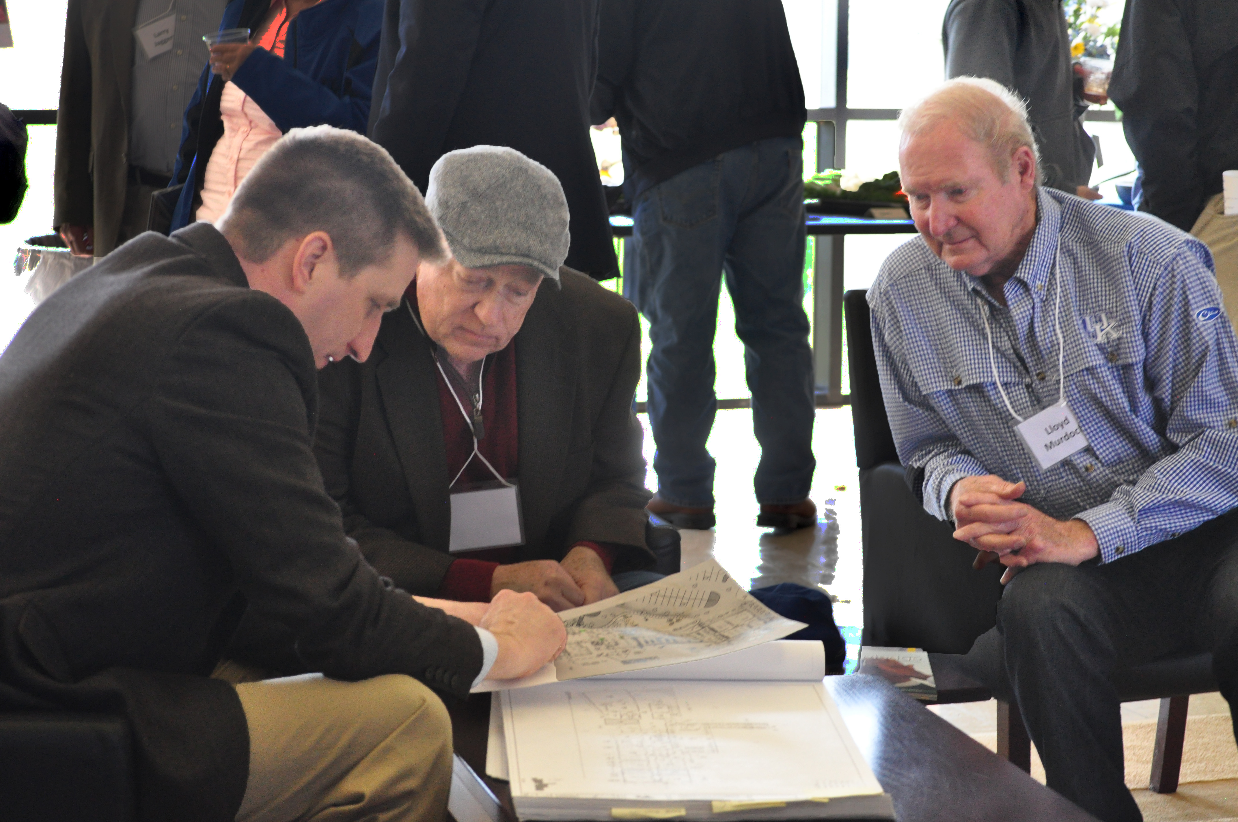 Three men look at blueprints together. 