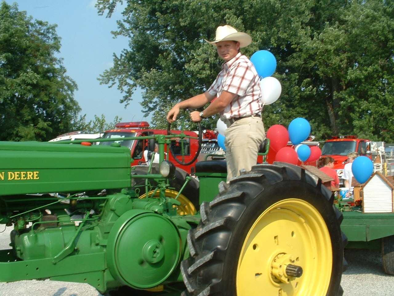 A man stands on a green tractor. 