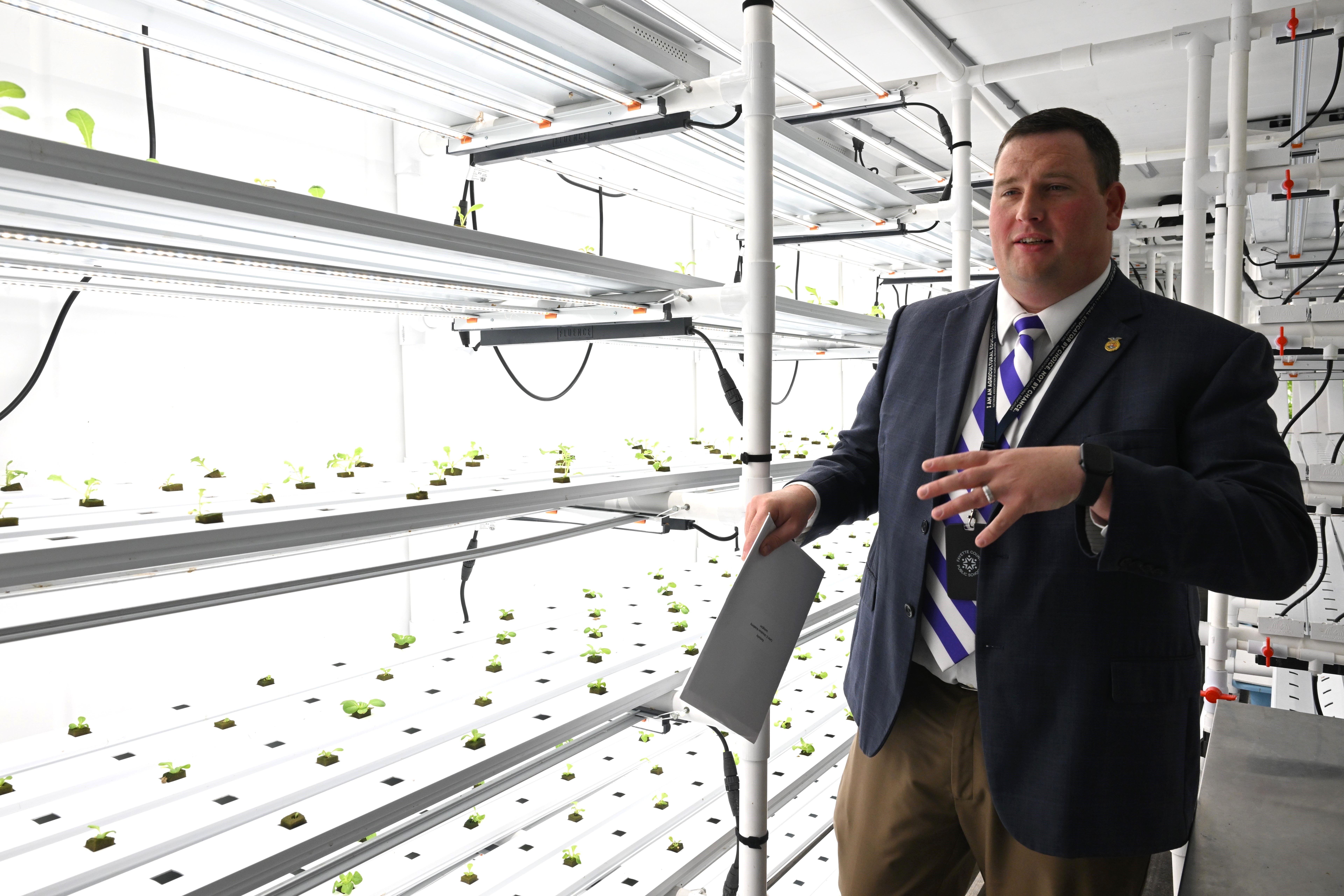 Jacob Ball giving visiting dignitaries a tour of the hydroponics farm at Carter G. Woodson Academy