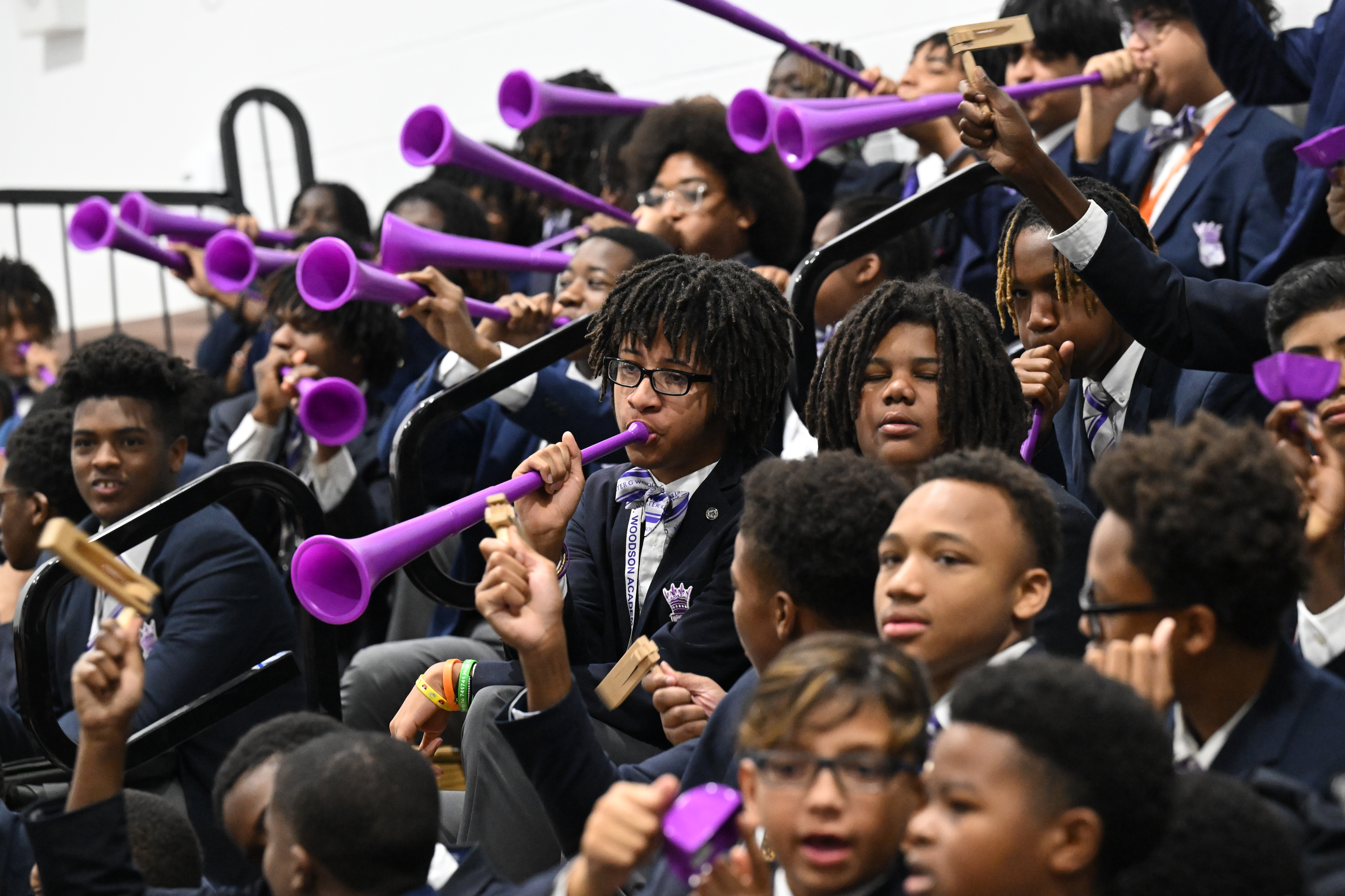 Carter G. Woodson Academy Scholars blow celebratory stadium horns in the school's signature purple to celebrate their teacher Jacob Ball.