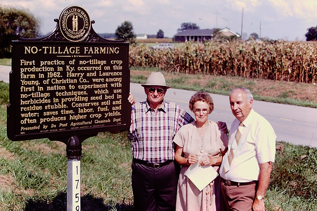 Harry Young, Marie Young and Shirley Phillips, UK agronomist, pose next to the No-Tillage Historical Marker on the Youngs' farm.