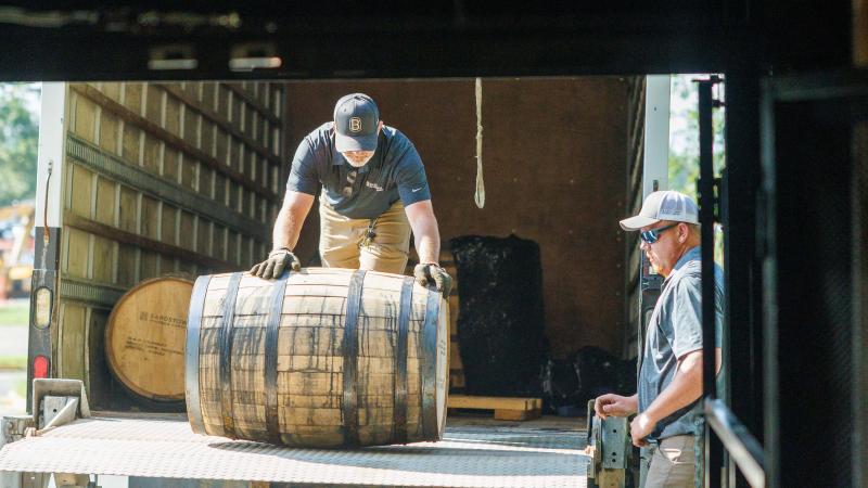 Man rolling bourbon barrel out of truck