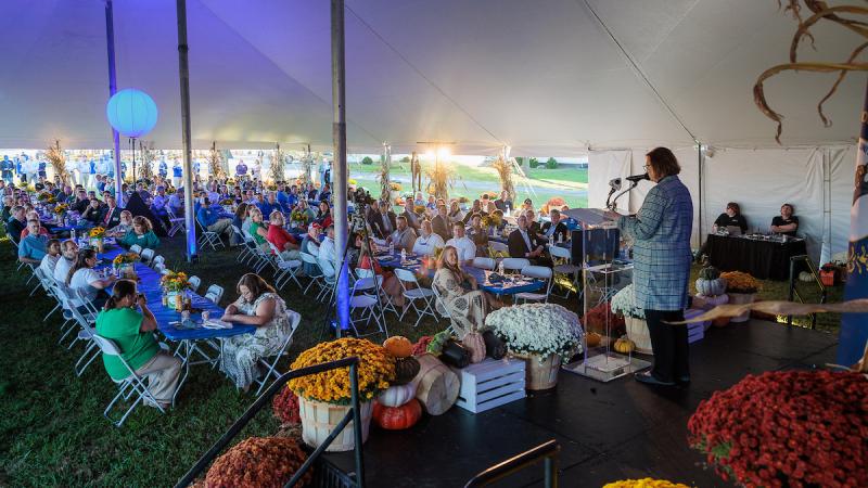crowd of people sitting in a tent listening to the dean of the Martin-Gatton College of Agriculture, Food and Environment at the UK Research and Education Center.
