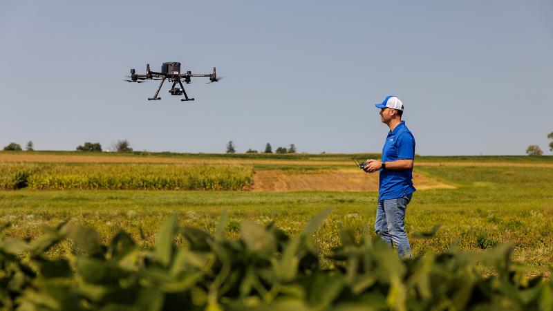 Drone and person operating drone on a farm with a blue sky. Photo by Matt Barton, University of Kentucky.