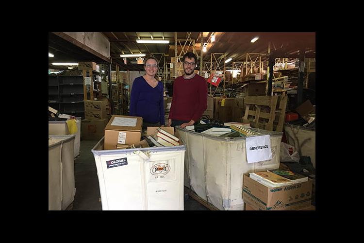 BAE's Carmen Agouridis and an IBP representative display donations from the 2017 Alpha Epsilon Book Drive