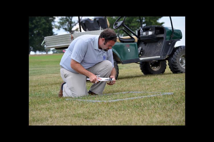 UK doctoral student Kenneth Cropper takes measurements in one of the lawn management systems at UK Spindletop Research Farm.