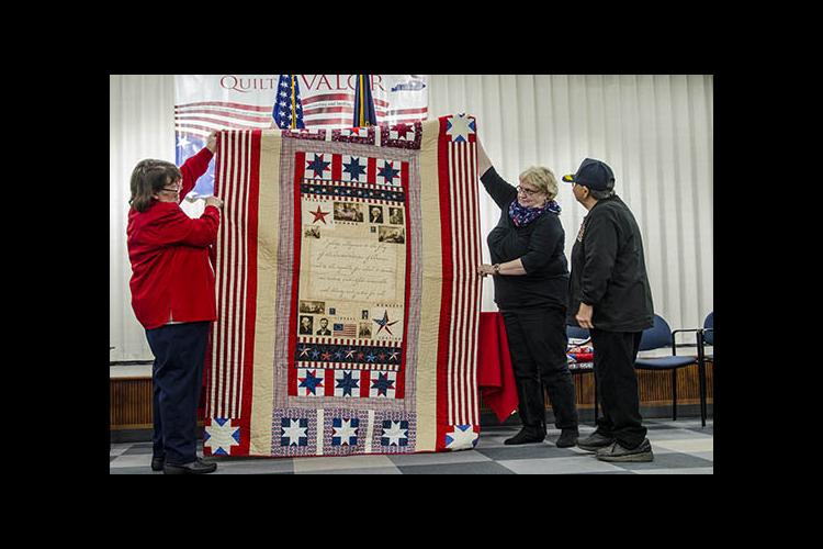 A quilt is awarded to a veteran during a Quilts of Valor ceremony at the Fayette County Extension office. 