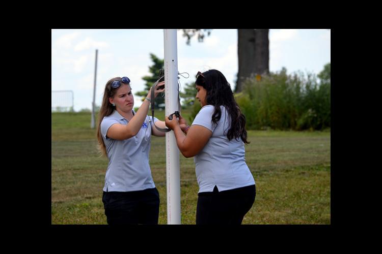 Diana Miller, left, and Abi Saeed of UK tie a wild game camera on the boundary of the turf entomology research plot.