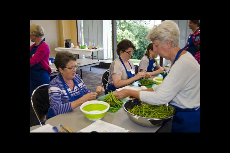 Cheryl Case, right, helps a food preservation workshop particpant break beans. 