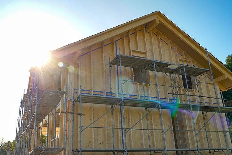 A lens flare over a cross-laminated timber house under construction