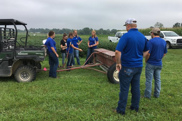 Grain and Forage Center of Excellence 2019 intern Hannah York, center, shows other interns how to calibrate a fertilzer spreader at the UK research farm in Princeton. Photo by Carrie Knott, UK grain crops specialist. 