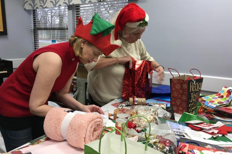Susan Bradley and Lee Clark wrap presents during a Joy of Giving event.