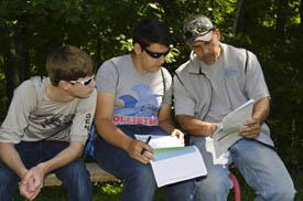 three students studying in woods