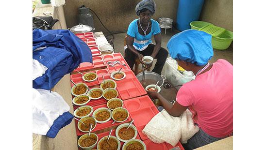 Female cooks serve food at the Kentucky Academy, a kindergarten in Adjeikrom, Ghana.