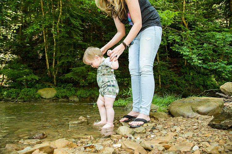 Baby dips its feet into a mountain stream in UK's Robinson Forest.